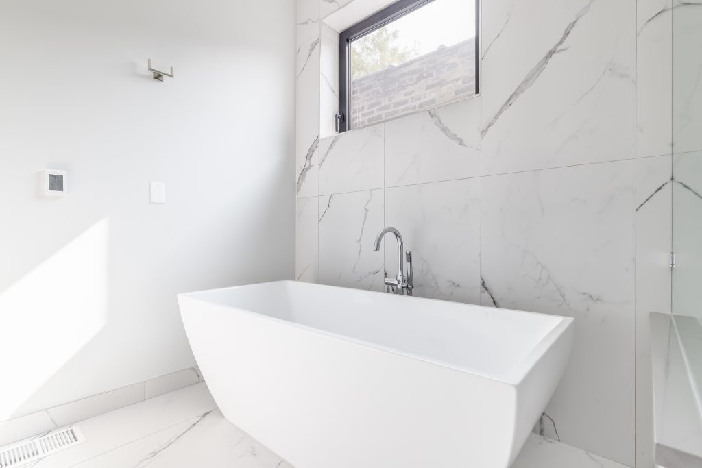 A standalone tub with marble floor and wall.