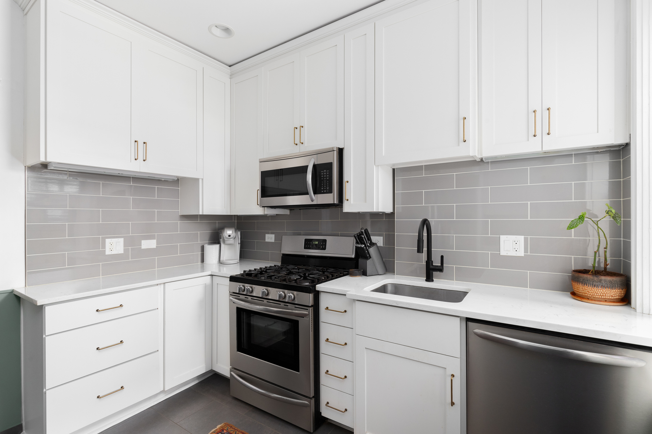 A small white kitchen with a grey subway tile backsplash.